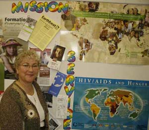 Anita Retzlaff standing beside a bulletin board cover in MCC posters 